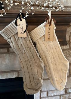 two stockings hanging from a mantel decorated with baby's breath and love tags