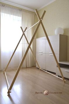 a room with a large wooden teepee on the floor in front of a window