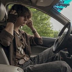 a young man sitting in the driver's seat of a car