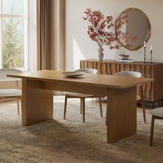 a dining room table with chairs and a mirror on the wall above it, in front of a large window