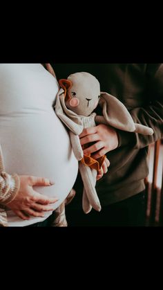 a pregnant woman holding a stuffed animal in her arms