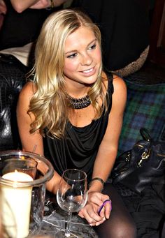 a woman sitting at a table with two wine glasses and a candle in front of her