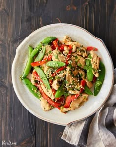 a white plate topped with chicken and veggies on top of a wooden table