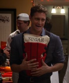 a man holding a giant red box with the word sugar on it