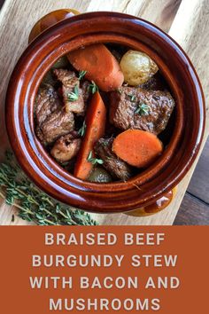 a bowl filled with beef and carrots on top of a wooden table