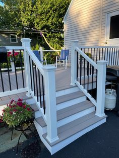 a porch with white railings and flower pots on the ground next to a house