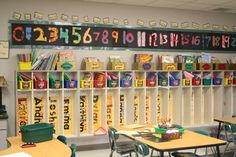 a classroom filled with desks and chairs next to a wall mounted book shelf full of books