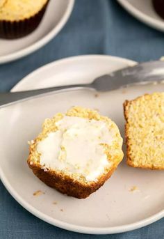 a muffin with frosting on a plate next to a fork and cupcake