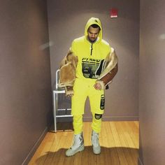 a man in a yellow outfit is standing on a wooden floor and holding a stuffed animal