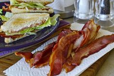 two plates with sandwiches and bacon on them