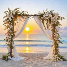 an outdoor wedding set up on the beach with white flowers and greenery at sunset