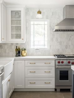 a kitchen with white cabinets and gold accents on the counter tops, along with a silver stove top oven