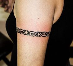 a woman with a tattoo on her arm has a black chain around her left arm