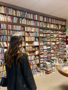 a woman standing in front of a library filled with books