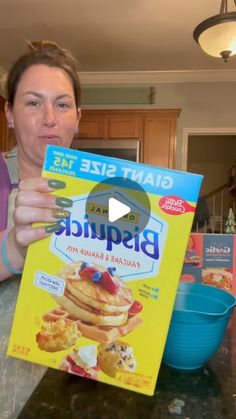 a woman is holding up a box of bisquick pancake batter mix in front of her face