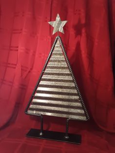 a small silver christmas tree on a black stand with a red curtain in the background