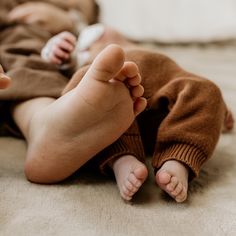 a baby is laying on the floor holding a remote