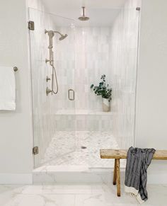 a walk in shower sitting next to a wooden bench and potted plant on top of a table