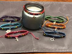 several bracelets and a candle sitting on a tablecloth with a gray vase in the background