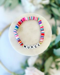 a bracelet with the word nurse written on it in front of some flowers and greenery