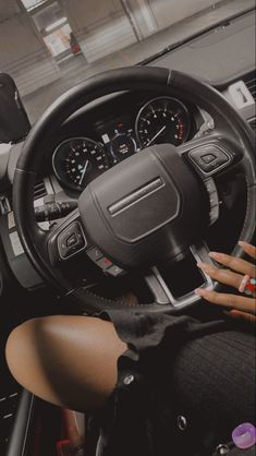 a woman sitting in the driver's seat of a car with her hands on the steering wheel