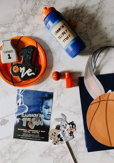 an assortment of sports related items on a marble counter top, including a basketball bottle and other personal items