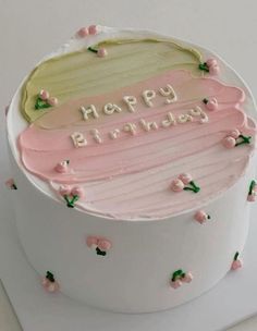 a birthday cake with pink frosting and green leaves on the top is sitting on a white surface