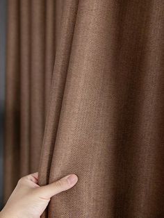 a person's hand is pulling up the curtain to reveal their brown color scheme