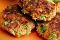 three crab cakes are stacked on top of each other with green peppers and seasoning