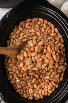 a wooden spoon in a slow cooker filled with beans