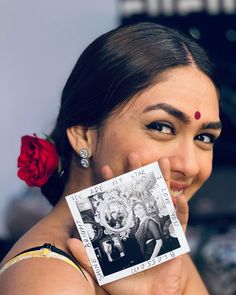 a woman holding up a small card with an image on it