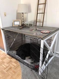 a dog laying in its cage on the floor next to a table with a ladder