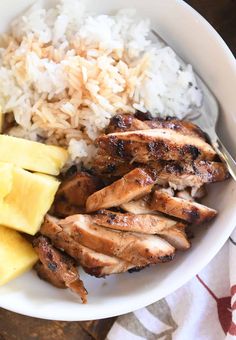 a white bowl filled with rice, meat and pineapple slices