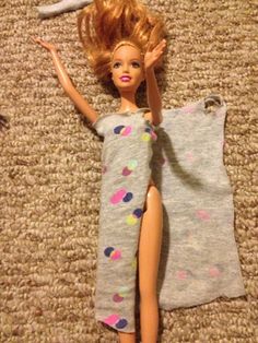 a barbie doll laying on the floor next to a pillow