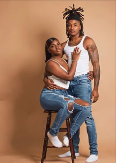 two people sitting on a stool posing for the camera with their arms around each other