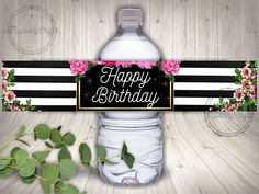 a happy birthday water bottle label with pink flowers and greenery on the top, sitting next to a wooden table