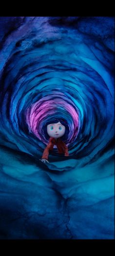 a doll is sitting in the middle of a blue and purple tunnel with light coming from it