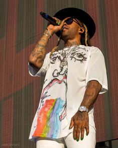 a man with dreadlocks holding a microphone up to his ear while standing on stage