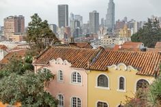 the city is full of tall buildings with red tile roof tops and trees in front of them