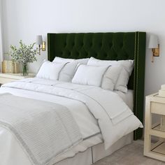 a bed with white linens and green headboard