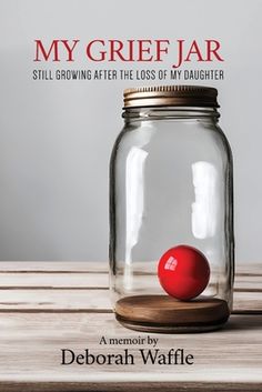 a red ball sitting in a jar on top of a wooden table