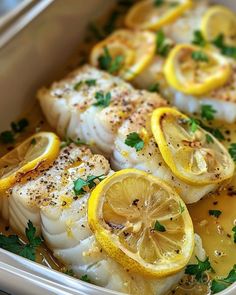 fish with lemons and herbs in a white dish