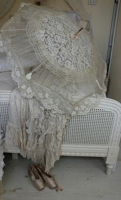 there is an old fashioned bed with lace on it and two umbrellas over the headboard