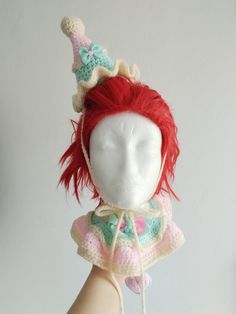 a doll with red hair wearing a crocheted unicorn hat on it's head