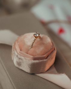 an engagement ring sitting on top of a pink velvet box