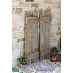 two wooden doors sitting on top of a table next to potted plants and a doily