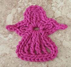 a pink crocheted object laying on the ground