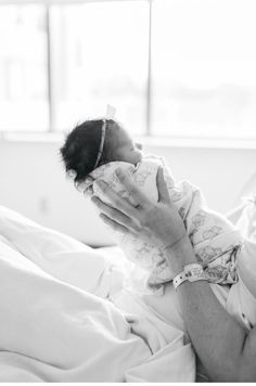 a black and white photo of a woman holding a baby in her arms while laying on a bed