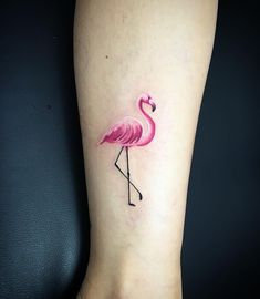 a small pink flamingo tattoo on the left side of the leg, with black outline