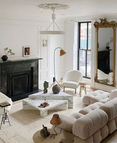 a living room filled with furniture and a fire place in front of a mirror on the wall